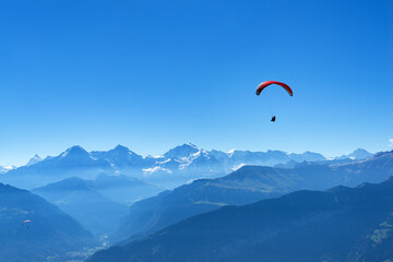 Fototapeta na wymiar Two hang glider flying in the air in front of the mountains Eiger, Mönch, Jungfrau