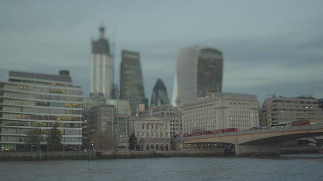 Queue of red buses on London bridge over Thames river in late evening