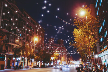 Illuminated town street with garlands and cars