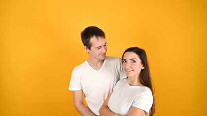 Young couple two friends guy girl in white empty blank design t-shirts posing isolated on yellow background.