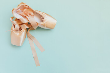 New pastel beige ballet shoes with satin ribbon isolated on blue background. Ballerina classical...