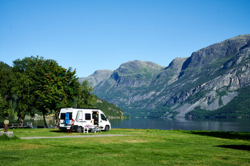Wohnmobil auf einem sehr schönen Campingplatz mit Bergen in Hintergrund und See - obrazy, fototapety, plakaty