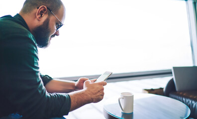 Serious man typing message on smartphone