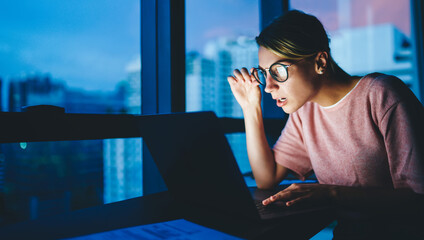 Surprised woman working on laptop in modern workspace