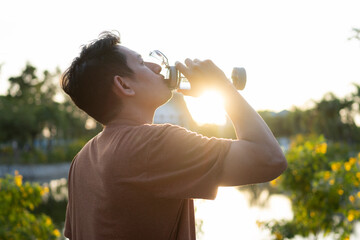 Tired man is drinking water bottle after run in the morning.