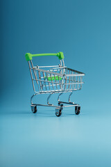 Empty shopping cart for goods from the supermarket on a blue background.