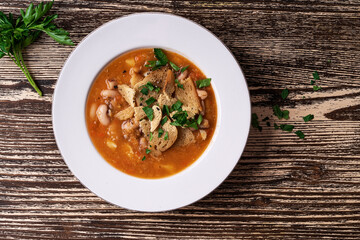 Bowl of tomato lentils soup with beans on wooden board