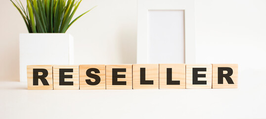 Wooden cubes with letters on a white table. The word is RESELLER. White background.