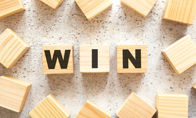 The word WIN consists of wooden cubes with letters, top view on a light background.
