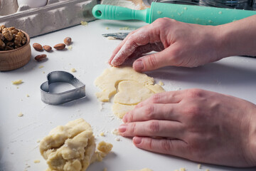 Girl carves cookies in the shape of a heart in the kitchen, at home, close-up. Handmade pastries with love for Valentine's day, mother's Day or father's Day. Culinary background. Holiday food