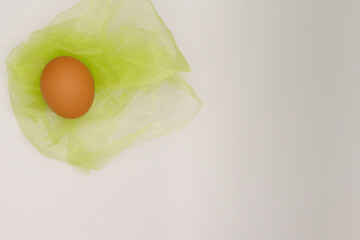brown egg on lime green textile against white background