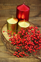 Christmas decoration, candles and holly on wood
