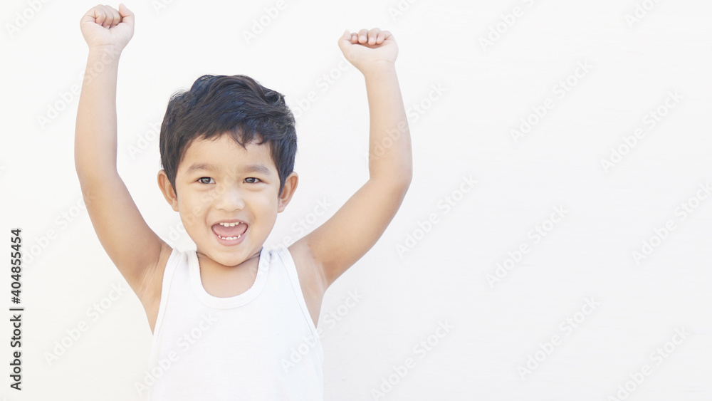 Wall mural Portrait of Asian boy winner with raised hands and clenching fists. Beautiful toddler kid shouting, isolated on white background. Happy cute child celebrating success with joy.