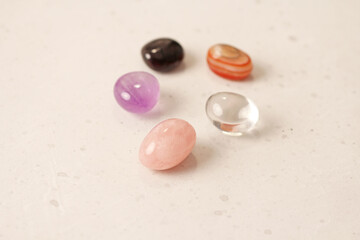 A set of natural stones lies on a light white background, garnet, amethyst, carnelian, rock crystal and rose quartz. Collection of natural stones, mineral and semi-precious stones