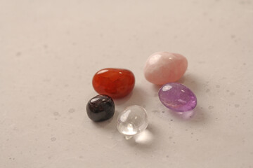 A set of natural stones lies on a light white background, garnet, amethyst, carnelian, rock crystal and rose quartz. Collection of natural stones, mineral and semi-precious stones