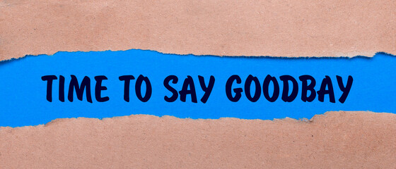 A strip of blue paper with the words TIME TO SAY GOODBAY between the brown paper. View from above