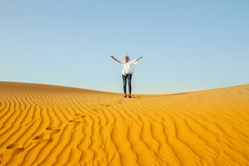 Fototapeta na wymiar Beautiful girl in the desert. Woman and Arabian sand dunes. Entertainment in UAE, Dubai