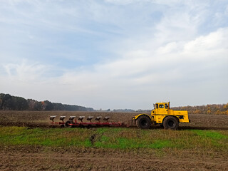 Agricultural yellow tractor, combine rides on the field, handles the ground, plough yells the...