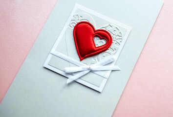 Valentine's day greeting card with a red heart isolated on a light pink background