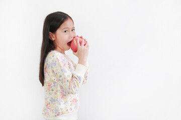 Little asian girl holding and bite red apple over white background. Side view