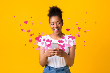 Black woman sending love message on cellphone, hearts flying away