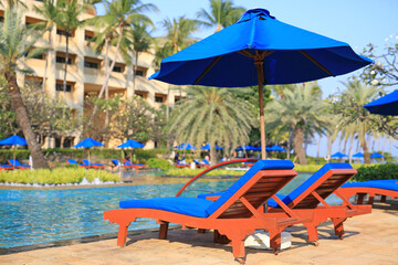 Empty lounge chairs near the pool in the sunny day.