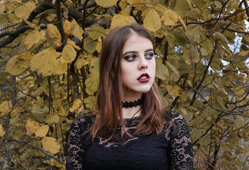 Portrait of a young girl with brown hair. Look away. Woman posing on a background of yellow leaves.