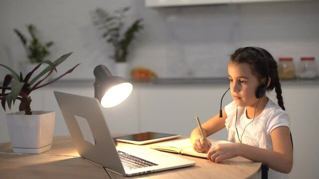 Little girl kid studen studying online class with laptop at home, New normal. Covid-19 coronavirus. Social distancing, home schooling.