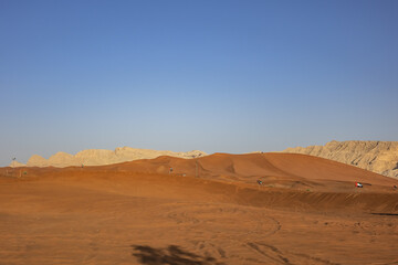 Fototapeta na wymiar Desert dunes at Al Awir desert near Dubai with buggy vehicle at sunset light. Dubai, United Arab Emirates, Middle East.