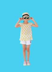 Smiling asian little girl wearing sunglasses and straw hat isolated on light blue background with clipping path. Summer and fashion concept. Front view and full length