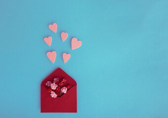 Isolated paper envelope with red roses and fly hearts over a blue background with copy space