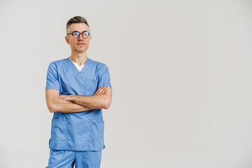 Happy white-haired medical doctor smiling and posing with arms crossed