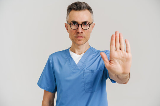 Displeased white-haired medical doctor showing stop gesture