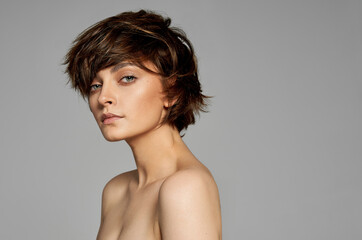 Beautiful woman with clean skin, natural make-up, and short hair on gray background