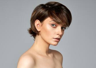 Portrait of sexy woman with clean skin, short hair on gray background