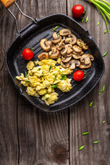 scrambled eggs with onion and mushrooms in frying iron pan, vertical image, place for text