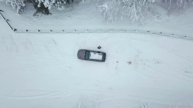 Aerial view from the top of the car drone, next to him waving and smiling young beautiful girl. The woman is happy, the drone flies vertically up. moving through an area surrounded by a beautiful coni