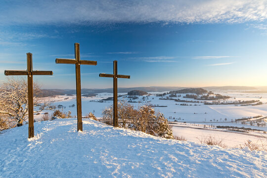 Three summit crosses on a mountain peak in a beautiful winter landscape in the Swabian Alps at sunset