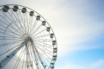Ferris wheel - giant observation wheel illuminated against blue sky.
