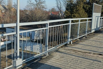part of an old gray concrete bridge with blue iron railings on the street