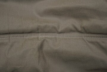 gray green fabric texture from crumpled piece of clothing and seam