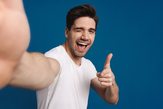 Happy Guy Winking And Pointing Finger At Camera While Taking Selfie