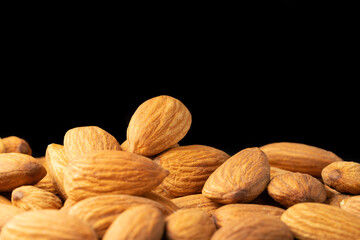 Raw almonds on a black background closeup. Macro, copy space.