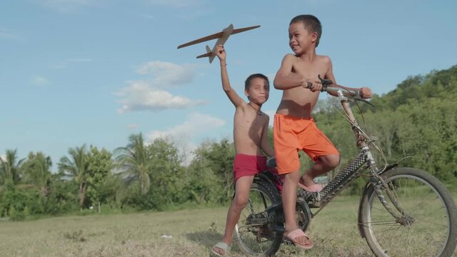 Rural Kids Riding Bike And Playing With Toy Airplane 

