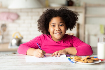 Portrait Of Happy Cute Little Black Girl Drawing In Kitchen