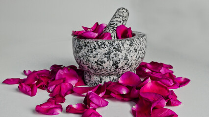 front view of granite mortar with pestle between pink rose petals