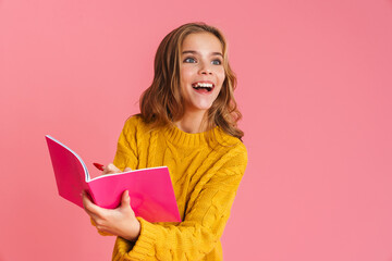 Happy beautiful blonde girl smiling while writing in exercise book