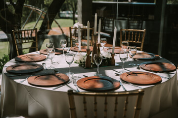 Table with white tablecloth, wooden plates and candles