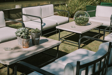 Armchairs and garden table adorned with pots, flowers and imitation leather fabrics.
