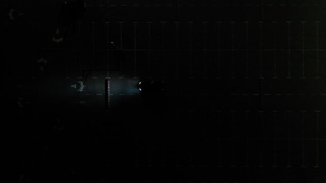 The car on the empty parking at night, aerial shot. Top down, top view, aerial drone footage of a black car driving and parking in a parking lot at night.